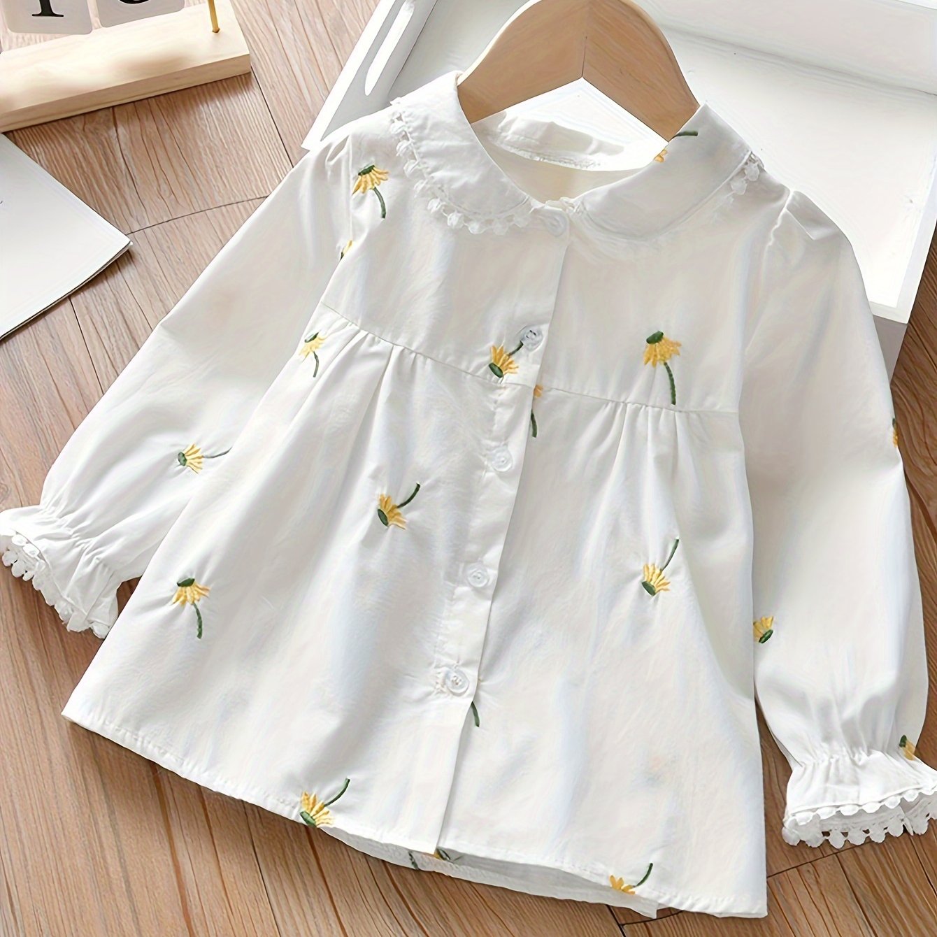 Girls' long-sleeve shirt with embroidered floral design, ideal for spring/fall. Casual and versatile in cotton blend fabric.