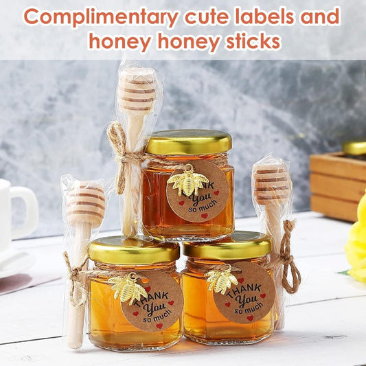 Tiny honey jars with wooden dipsticks, hexagonal glass containers topped with golden lids, embellished with charming golden bee accents, and accented with decorative jute perfect for weddings, baby showers, and party favors.