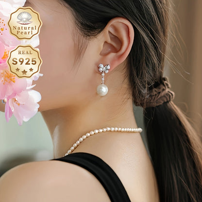 These women's fashionable dangling earrings feature a pair of 12-13mm large grains of strong light, slightly flawed round natural freshwater pearls set in S925 silver. Each earring is adorned with a delicate bow and comes in a gift box. Please note that