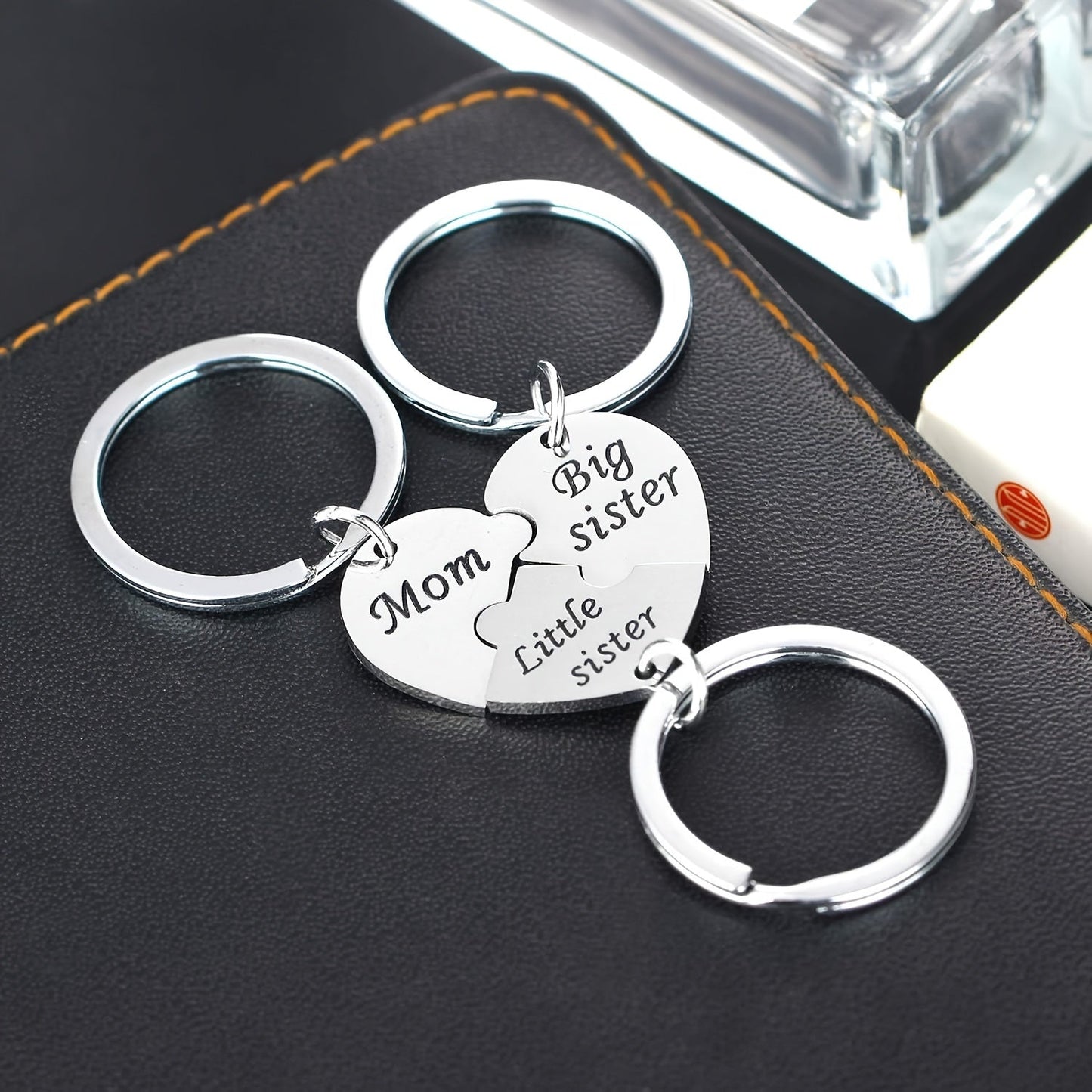 Set of three heart-shaped keychains for mothers and daughters, engraved with "Mom," "Big Sister," and "Little Sister." This matching pendant accessory set symbolizes family connection.