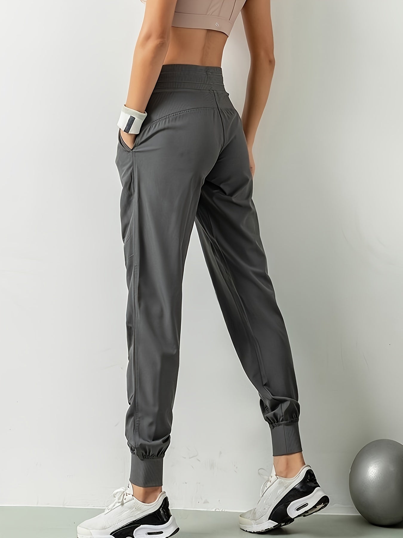 Women's solid color sports pants with drawstring waist, quick drying material, and side pockets for casual comfort.