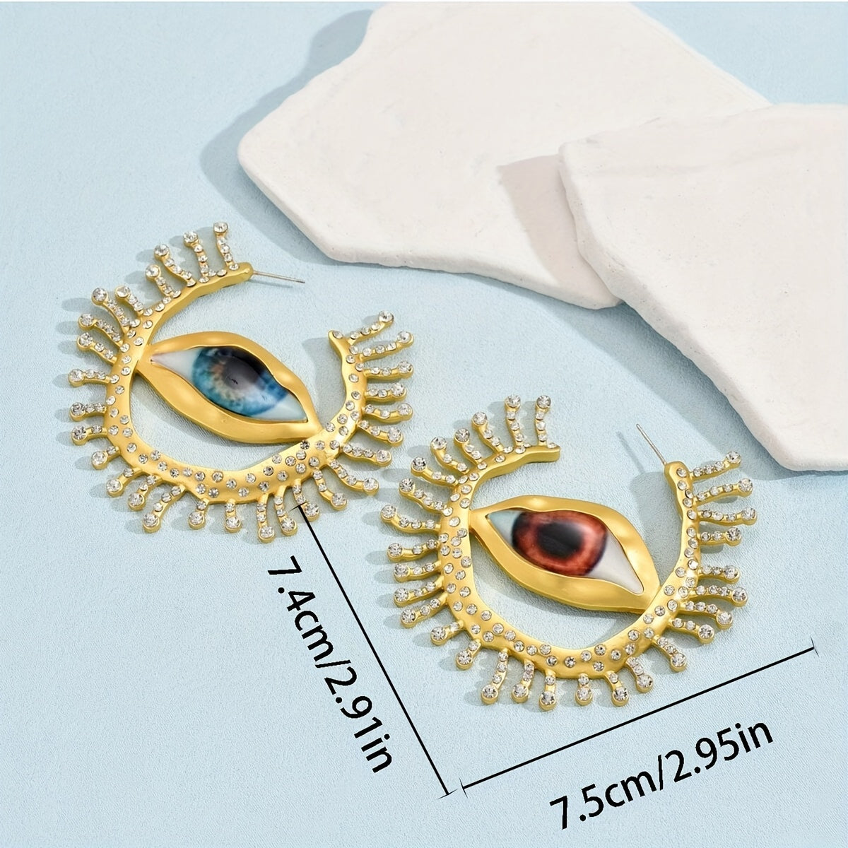 These punk cool style statement earrings feature an exaggerated eye-shaped design with metallic rhinestones. Perfect for parties, vacations, and everyday wear. Add a unique touch to your jewelry collection with this bold pair of dangle earrings.