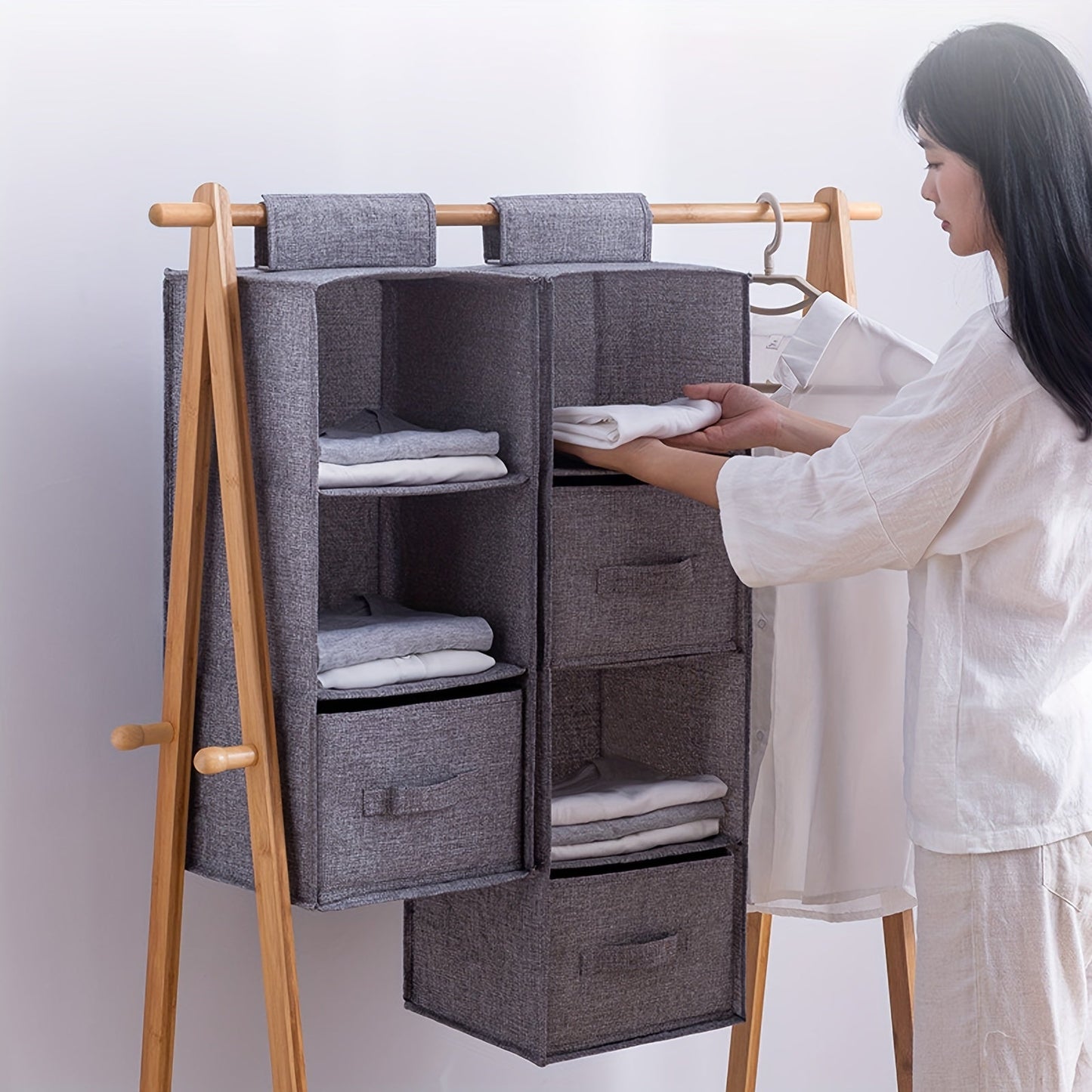 This durable gray storage solution is a 4-tier foldable hanging clothes organizer with sturdy handles. It is ideal for wardrobes and bedrooms, perfect for storing clothing, blankets, and quilts. The space-saving design makes it a convenient addition to