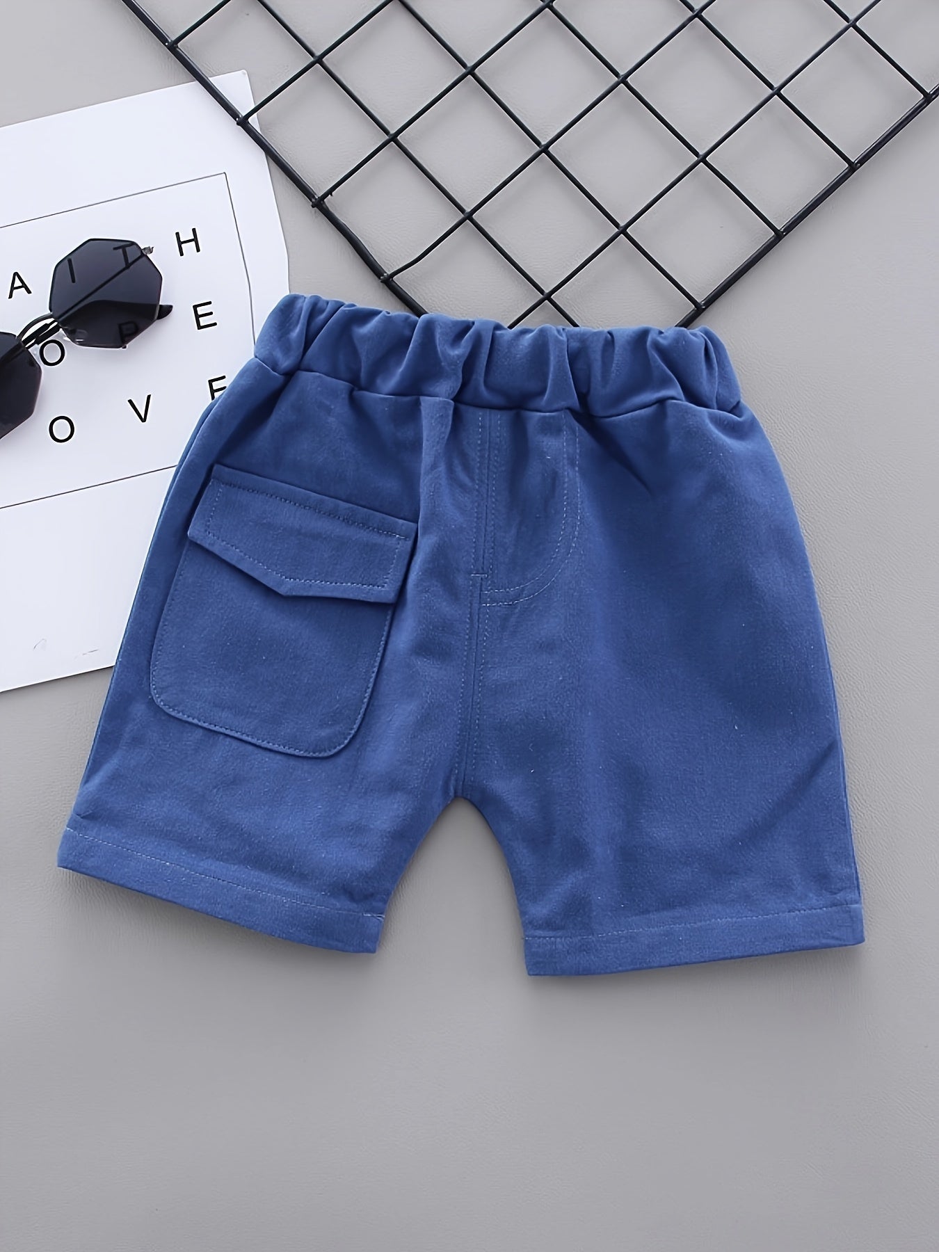 Boys' Dinosaur Cartoon Shirt & Shorts Set in soft cotton blend with white short-sleeve top and blue chevron pattern. Includes dark blue denim shorts for a casual summer outfit. Ideal for