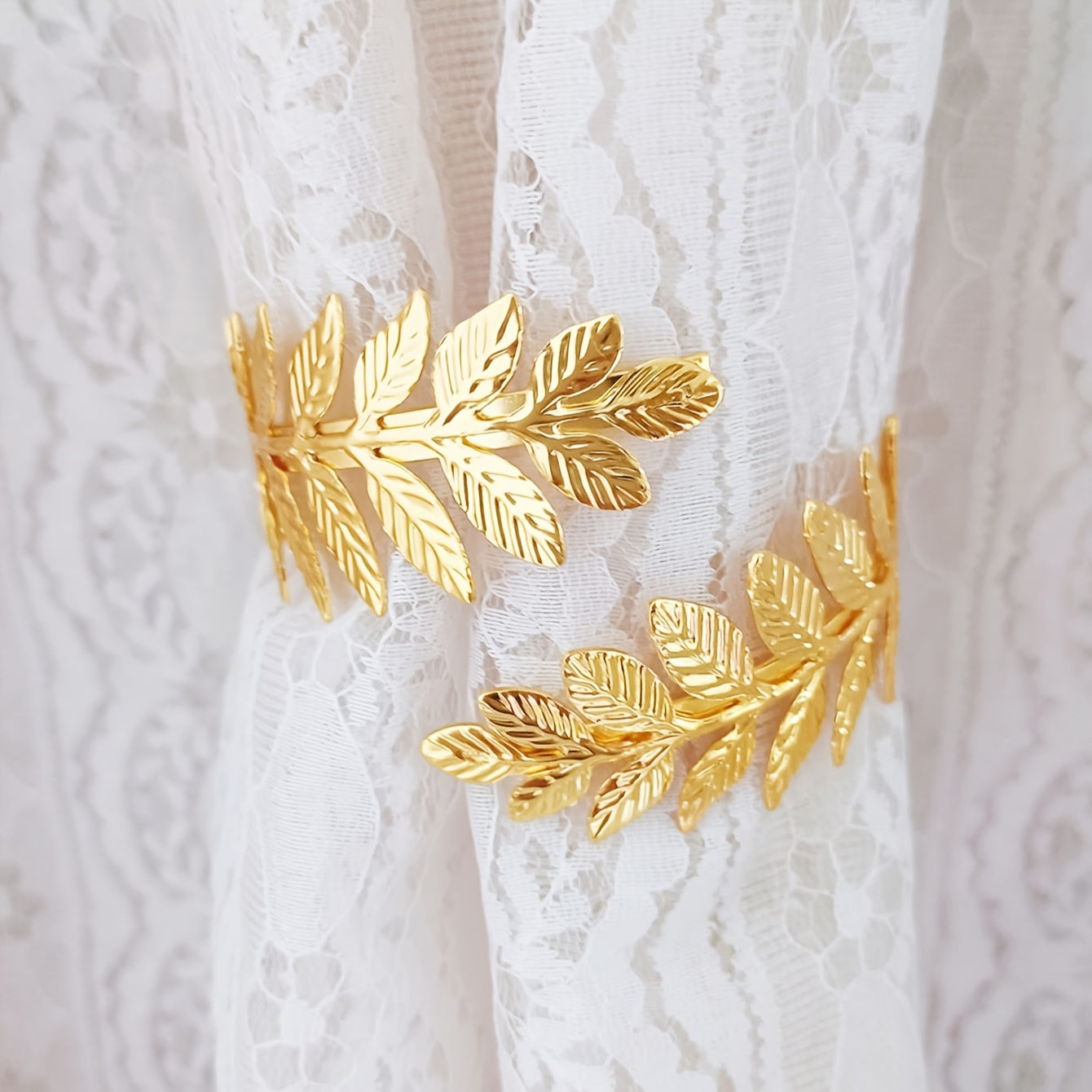 A decorative curtain tieback with gold accents, adorned with branches, leaves, and leaf-shaped hooks, perfect for enhancing home decor.