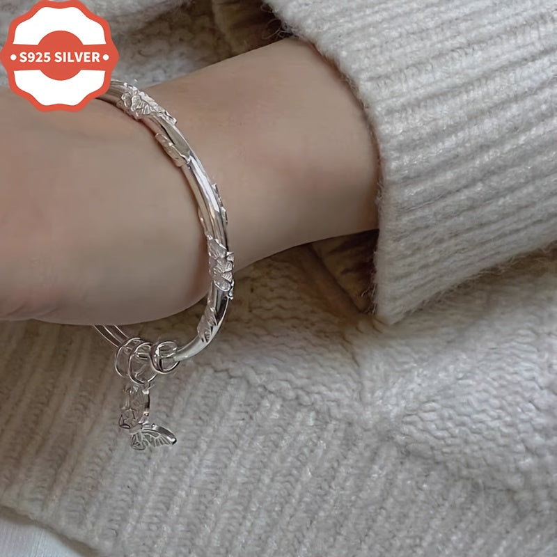 Add a touch of boho luxury to your wardrobe with this stunning 925 silver bangle bracelet featuring 18K golden plated charms. Handcrafted with floral designs, butterfly, and bell pendants, this hypoallergenic cuff is perfect for women who love unique