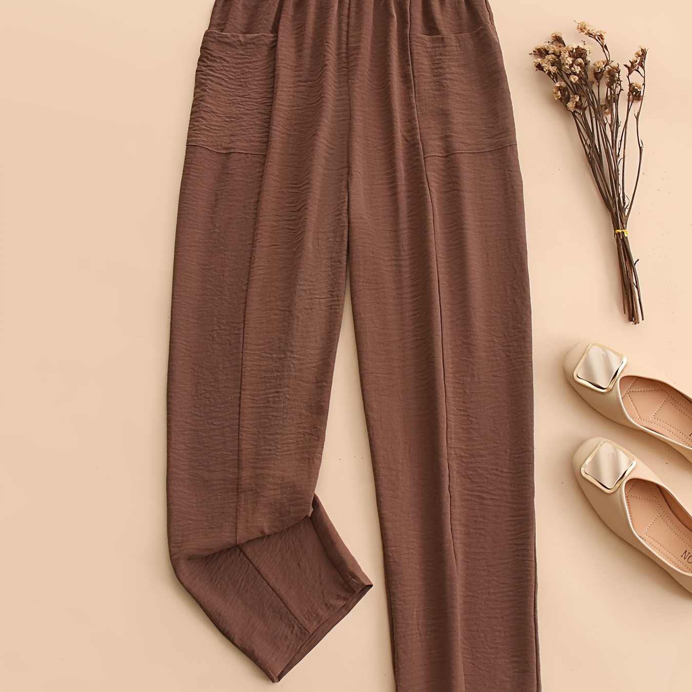 Brown harem pants for women with pockets. Elastic waist, loose fit, and machine washable. Made of casual polyester for all-season comfort. Clothing essential for wideleg trousers.