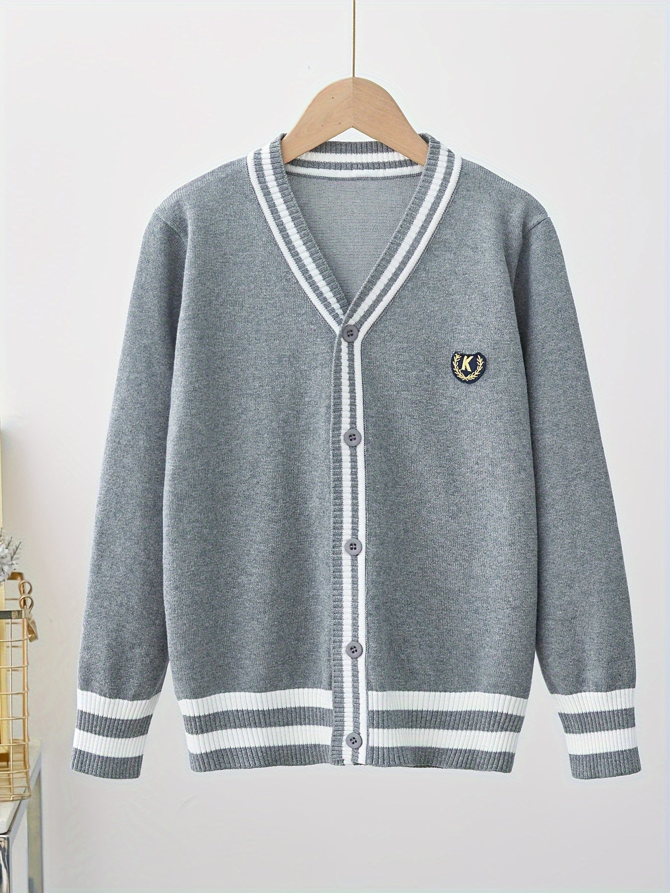 Youngsters' black and white striped V-neck cardigan with "K" logo, suitable for boys and girls in spring and fall. Perfect for school uniforms, stylish and versatile.