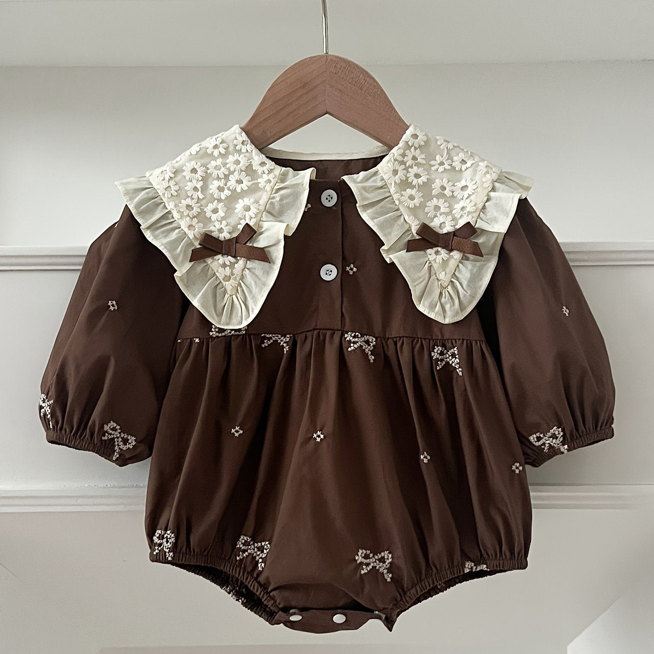 Stylish floral embroidered long-sleeve romper for baby girls, made of cotton with bow detail, ideal for spring/fall and outdoor wear.