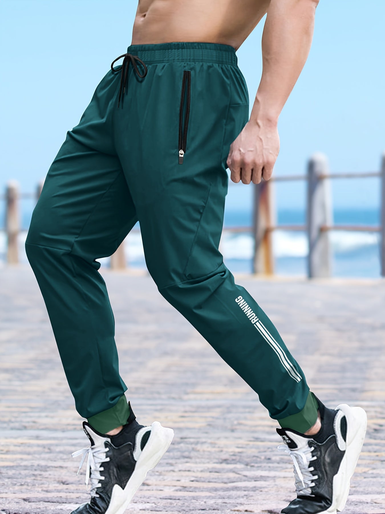 Men's solid color cuffed sports pants made of 100% polyester with moisture-wicking properties. Features a drawstring waist, loose fit, and quick-dry technology for various activities and