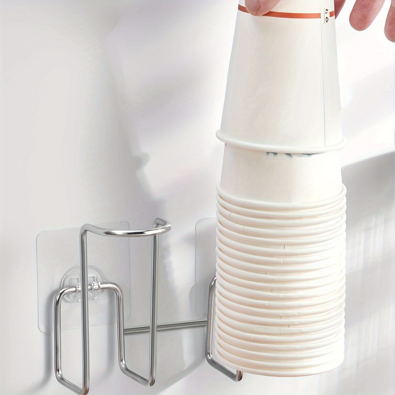 Wall mounted storage organizer for disposable paper cups, made of stainless steel and plastic. Suitable for use in offices, kitchens, and homes, this punch-free rack is designed to hold cups for water dispensers.