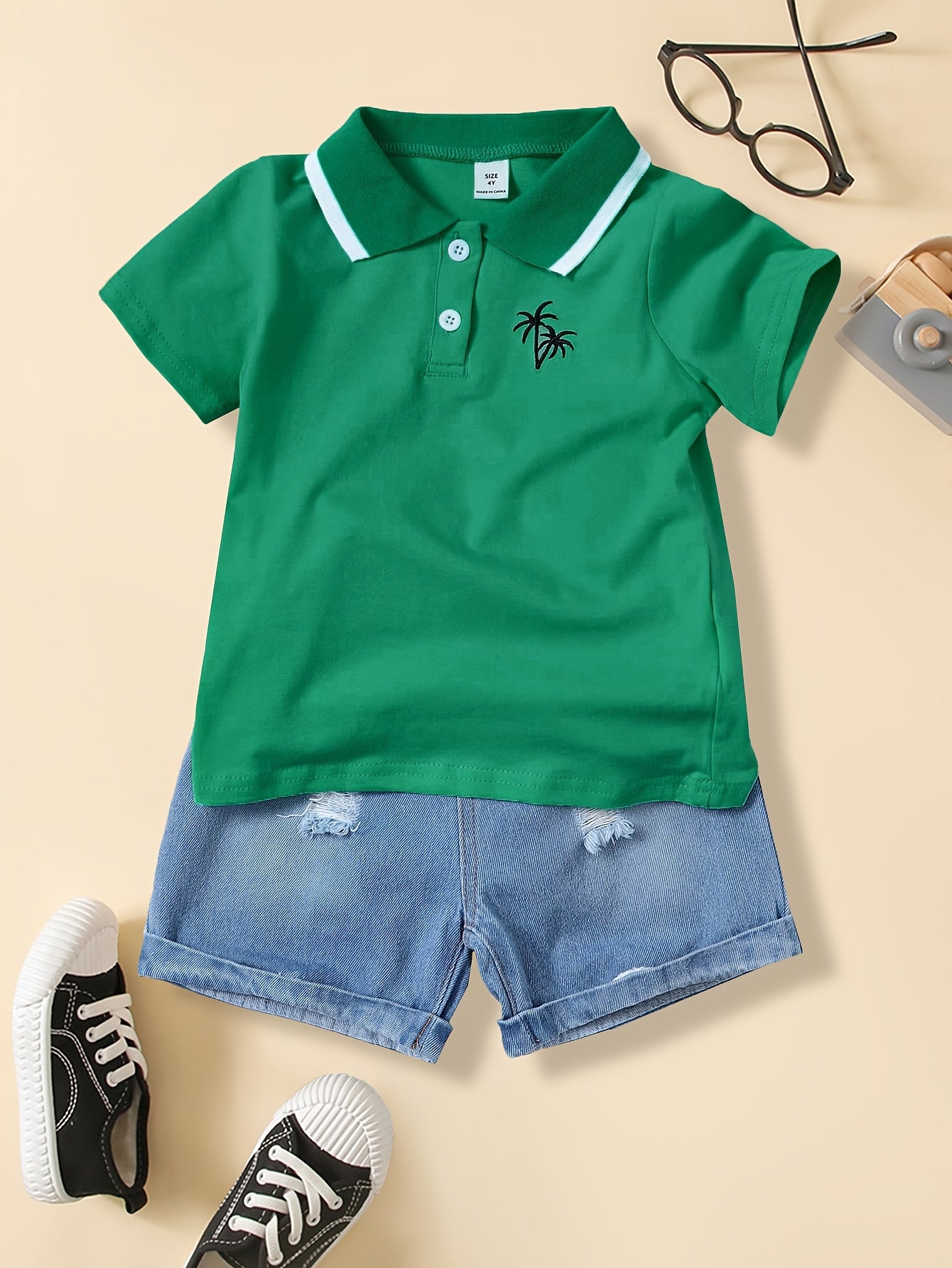 Boys' casual t-shirt with coconut tree design, made of polyester blend with medium stretch. This short sleeve top features a lapel collar and button detail, perfect for weekends. Suitable