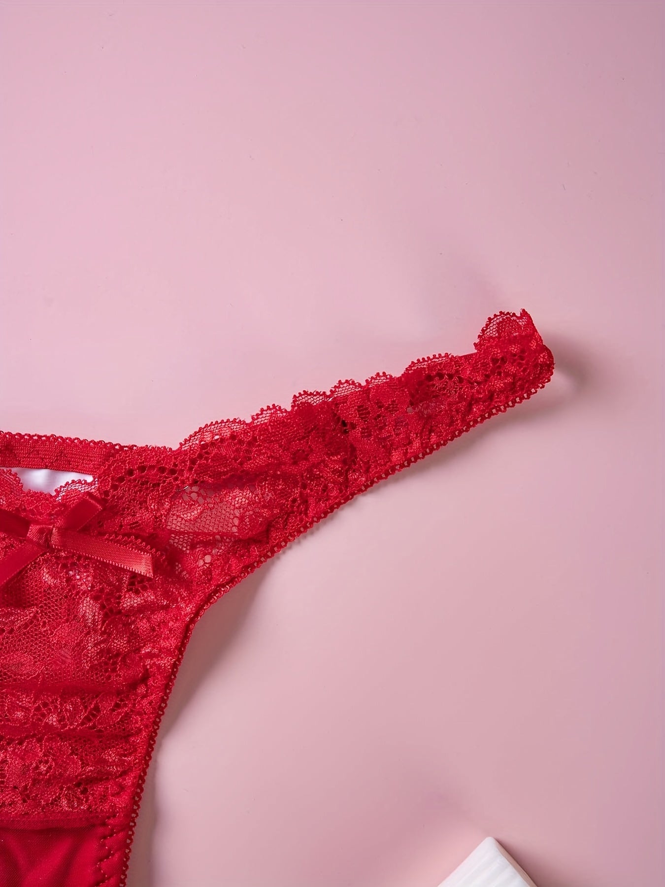 Red lace thong panties with floral print and bow detail, low rise V-shaped design. Made of breathable polyester blend, hand washable. Ideal for intimate moments.