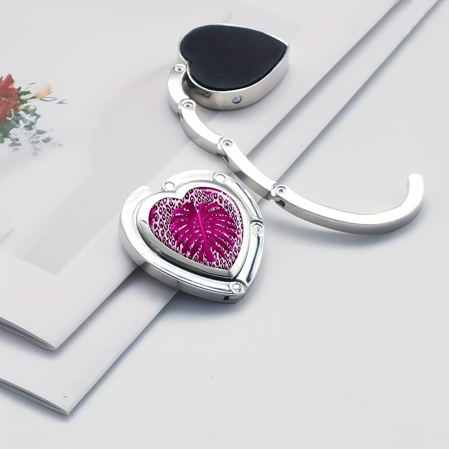 Heart-shaped purse hook with exquisite print, designed to fold for easy storage. Hang bags on tables and desks with style.