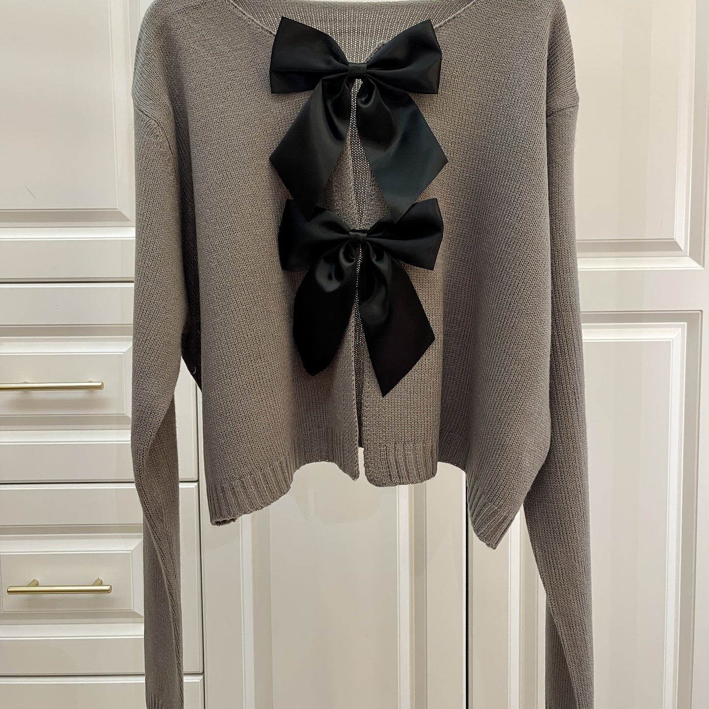 Stylish women's lightweight acrylic knit cardigan with large bow tie, perfect for spring and fall. White with black bow detail.