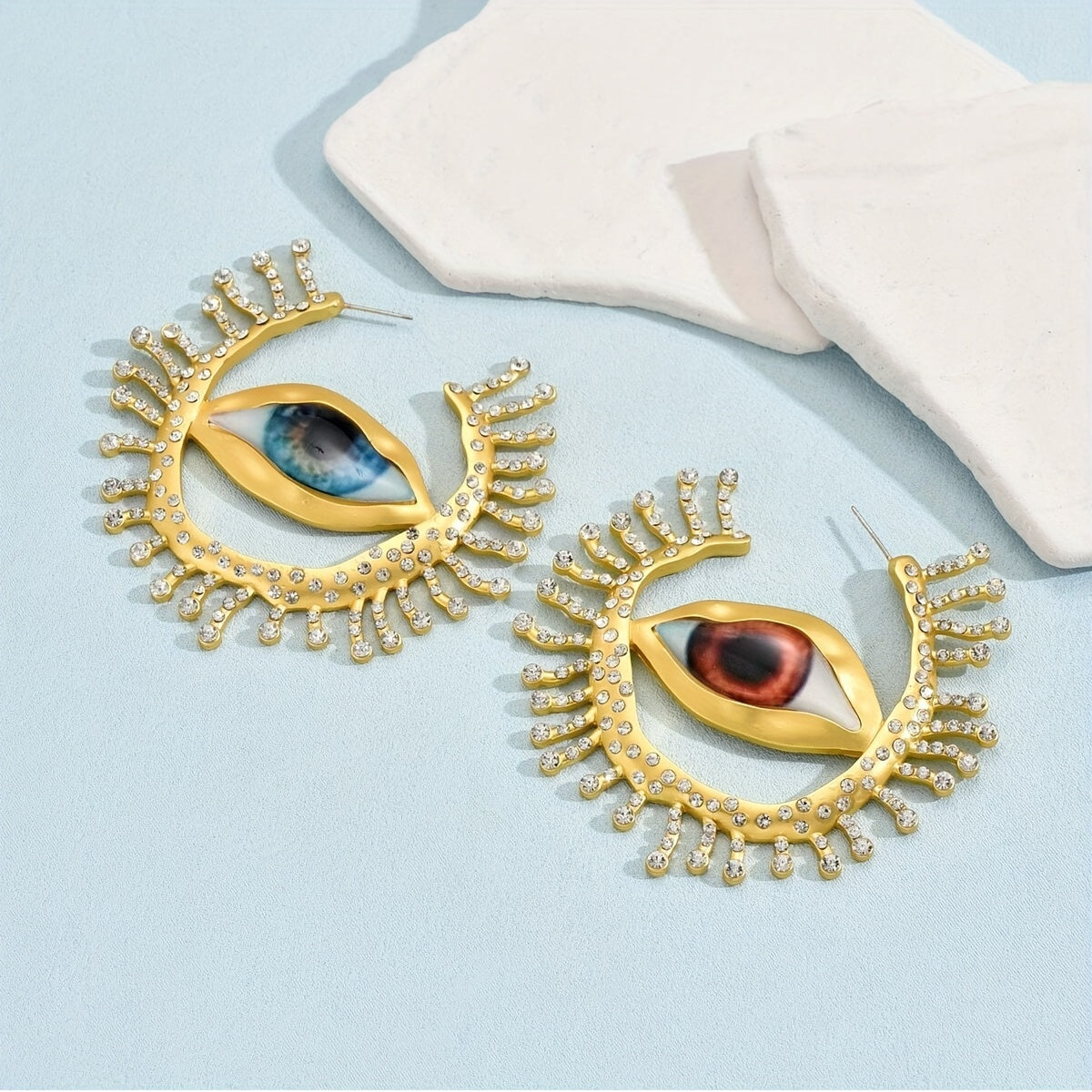 These punk cool style statement earrings feature an exaggerated eye-shaped design with metallic rhinestones. Perfect for parties, vacations, and everyday wear. Add a unique touch to your jewelry collection with this bold pair of dangle earrings.