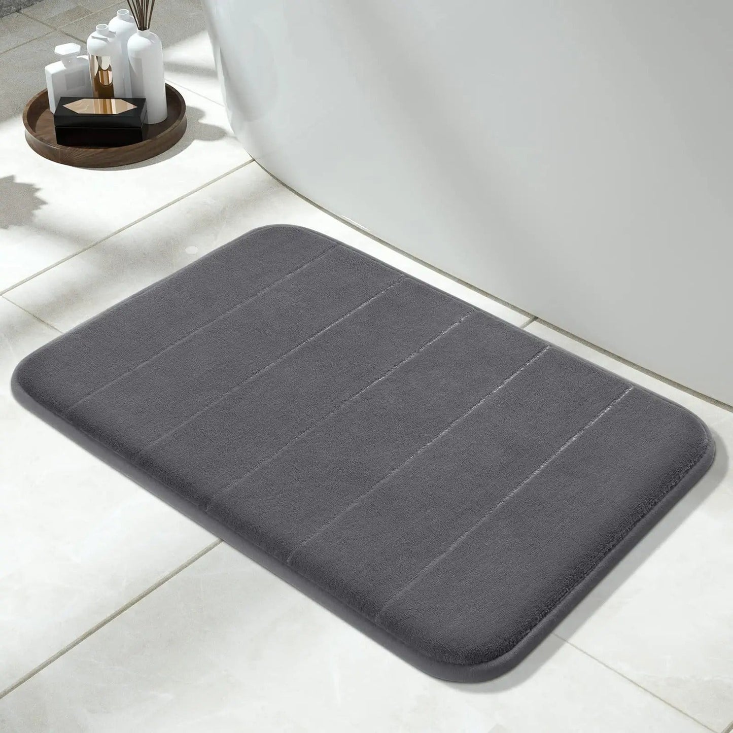 Soft polyester blend bath mat in plush dark gray stripes, featuring a non-slip PVC backing for added safety. Easily machine washable for convenience, this rectangular mat is perfect for adding comfort to your bathroom décor.