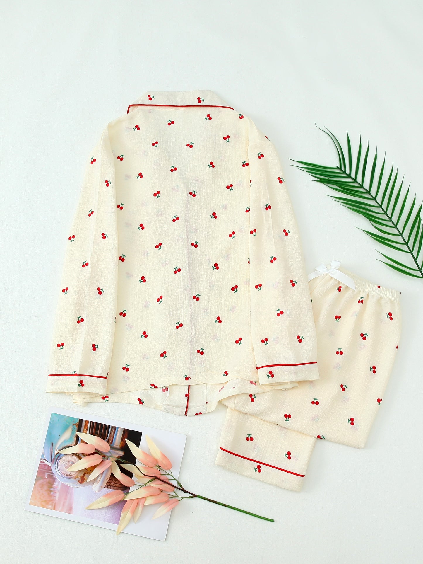 Women's cherry print pajama set with bow tie detail, long sleeve top, and long pants in polyester material, suitable for all seasons.