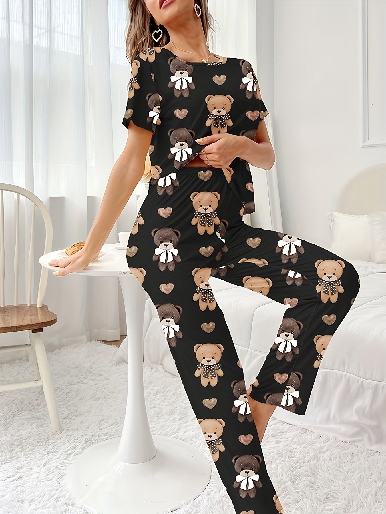 Women's sleepwear set with cartoon bear and heart print, featuring a cozy short sleeve top and elastic pants.