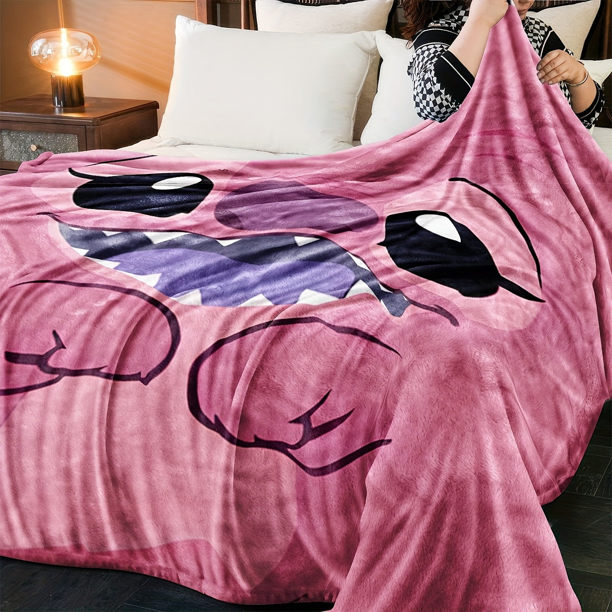 Pink plush throw blanket featuring a contemporary cartoon design. Made from soft polyester knit fabric, this multipurpose bedding is suitable for all seasons. Perfect for adding comfort to your bed, sofa, office nap, or as a travel blanket. Makes an