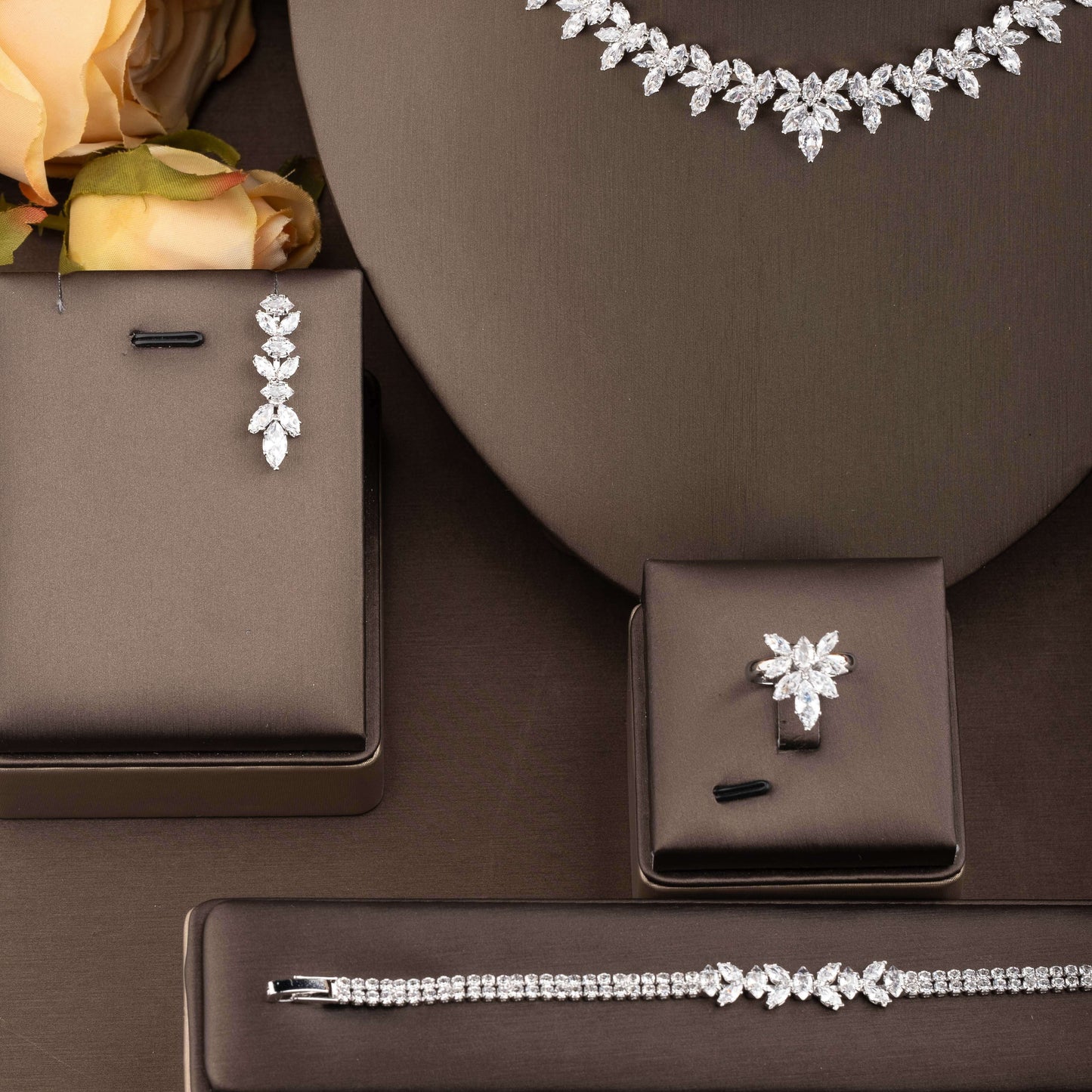 Exquisite set of jewelry adorned with cubic zirconia leaf detailing, including a necklace, earrings, ring, and bracelet, designed for women to enhance their ensemble for weddings and galas.