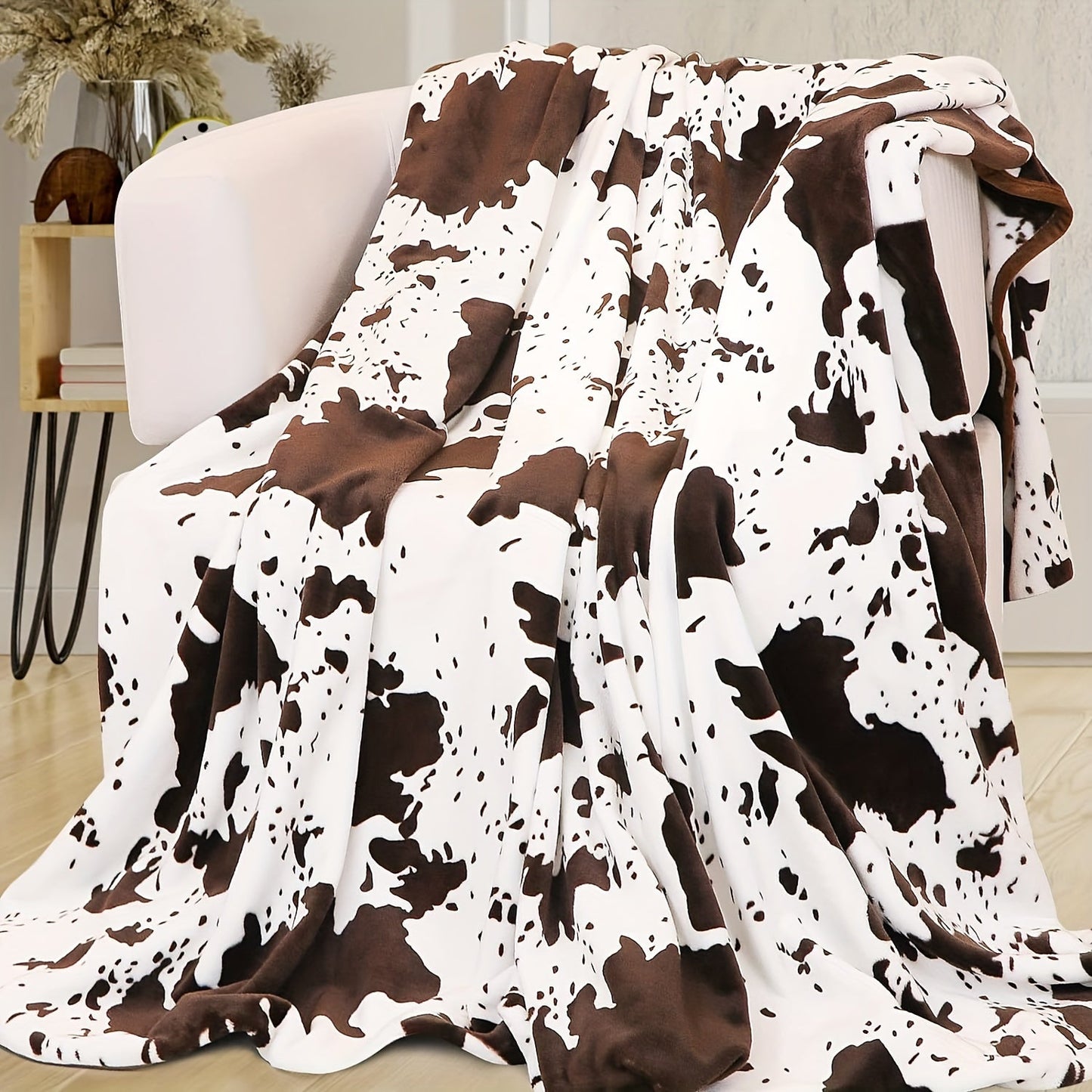 Soft and lightweight, this plush flannel blanket in a cozy cow print is made of 100% polyester for all-season comfort. Perfect for snuggling on the couch or taking on travel adventures, its adorable brown and white design adds a touch of charm to any