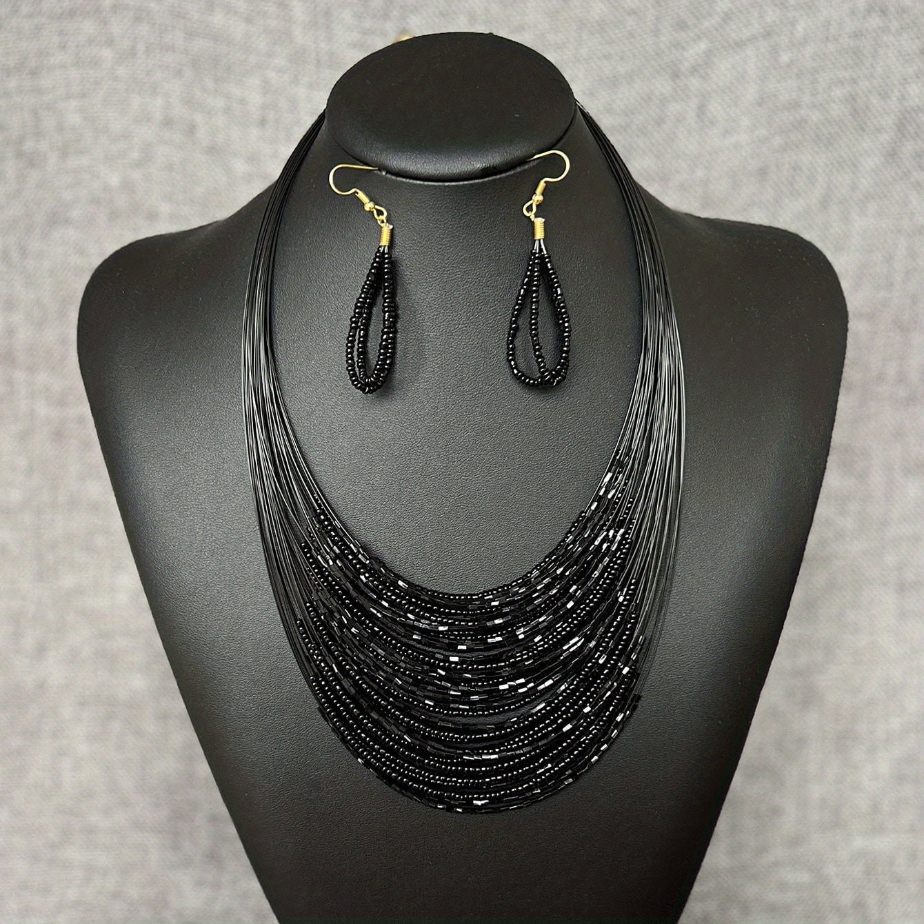 A set of three handmade earrings and a necklace crafted from elegant black beads in a multi-layer design, representing both evil and mystery. Perfect accessories to complete your daily outfits or add flair to your party attire.