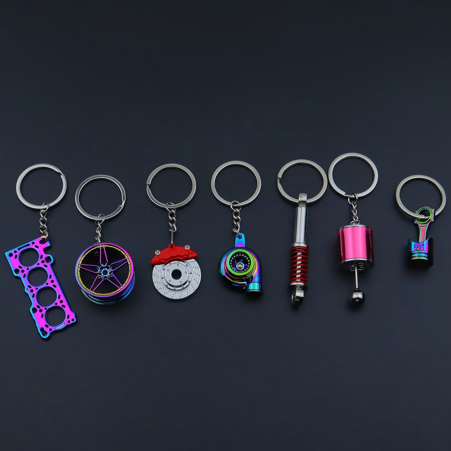 Funky car modification keychains set includes seven pieces: piston, turbo, wheel hub, gear shift, shock absorber, brake disc, and engine block. Made of zinc alloy in a sleek black finish.