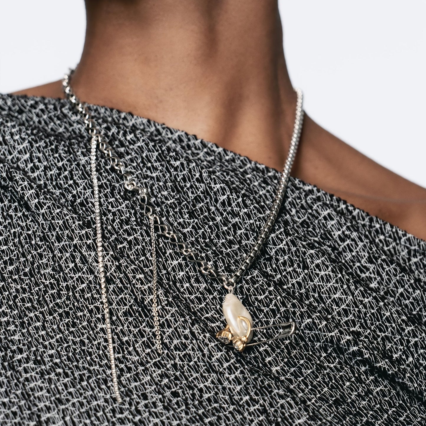 This Unique Pin Pendant Necklace features an elegant asymmetrical chain design adorned with Zirconia and Faux Pearl accents. Perfect for dressing up casual attire or as a thoughtful gift, this creatively designed pendant adds a touch of sophistication to