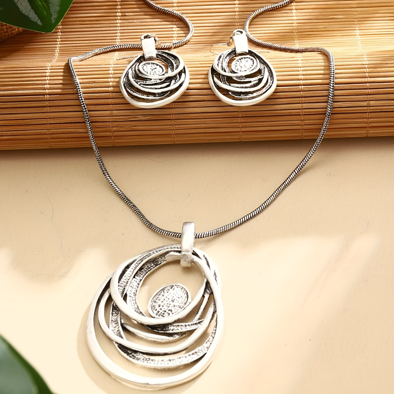 This set includes a pair of earrings and two necklaces made of zinc alloy in an ancient silvery color. The necklaces feature a multi-layer circular mosaic design with a retro bohemian style and a hollow center. This leisure jewelry set is perfect as a