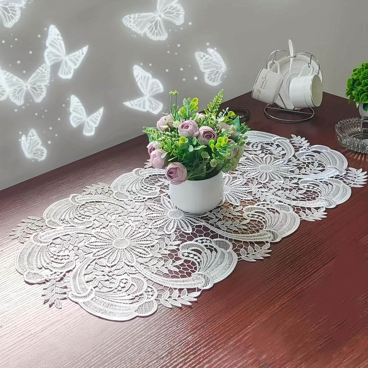 White velvet lace oval table runner with floral pattern, perfect for holiday table setting. Butterfly motif on decorative fabric for dining and home decor.