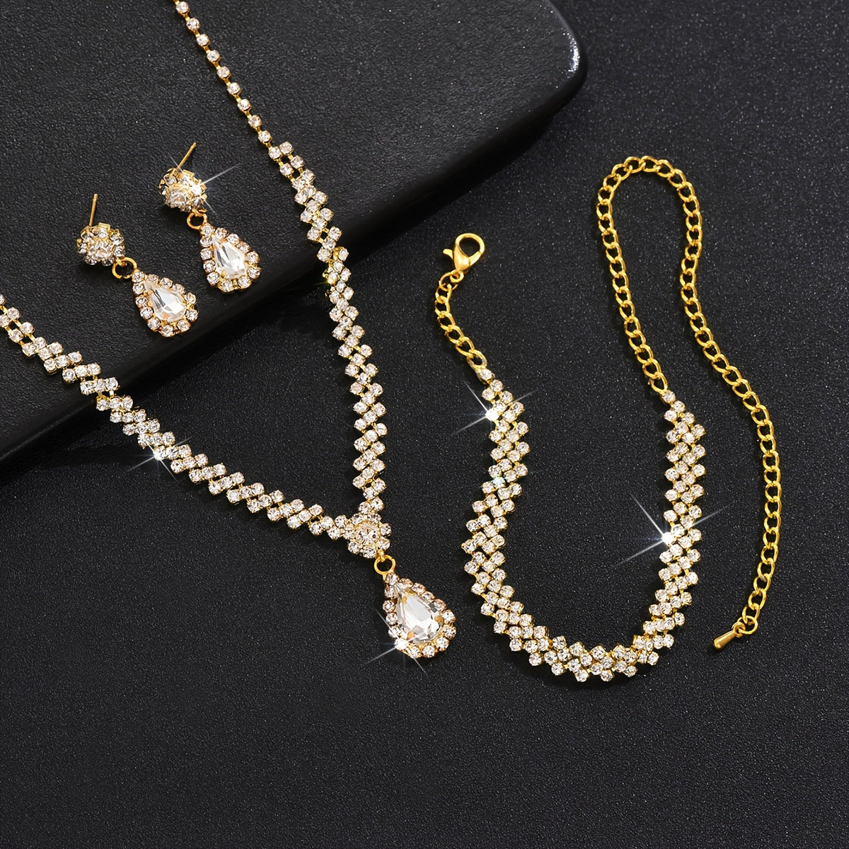 1 set of trendy female wedding decor jewelry, including dangle earrings, a necklace, and a bracelet all featuring a water drop pendant design with rhinestones inlaid.