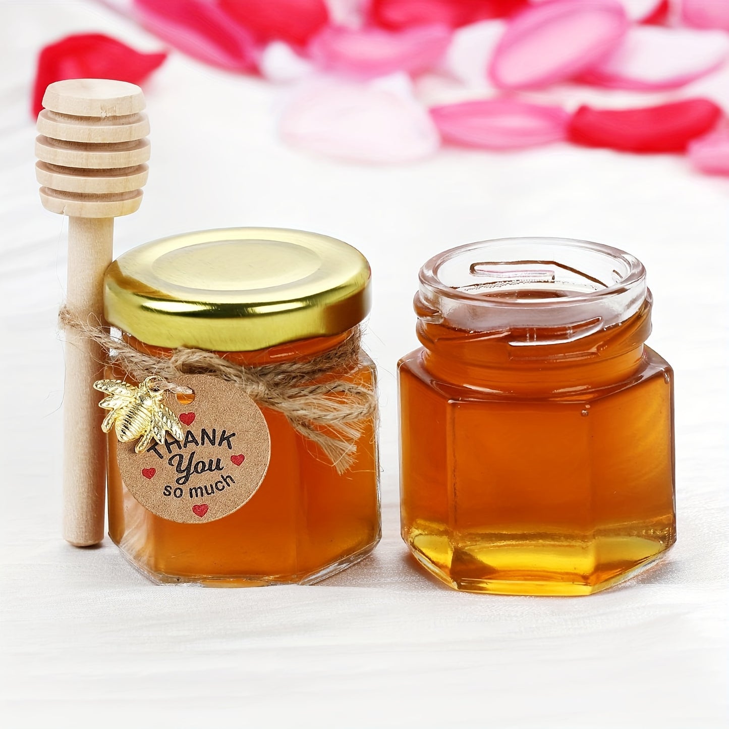 Small hexagonal glass honey jars come in 1.5 oz sizes in sets of 20, 30, 50, or 60. Each jar includes a spoon, bee symbol, and thank you card. They have golden lids and are ideal for baby gifts, weddings, and parties.