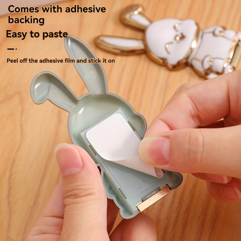 Foldable waterproof phone stand made of ABS material, featuring an adjustable cartoon bunny design for holding smartphones and tablets.