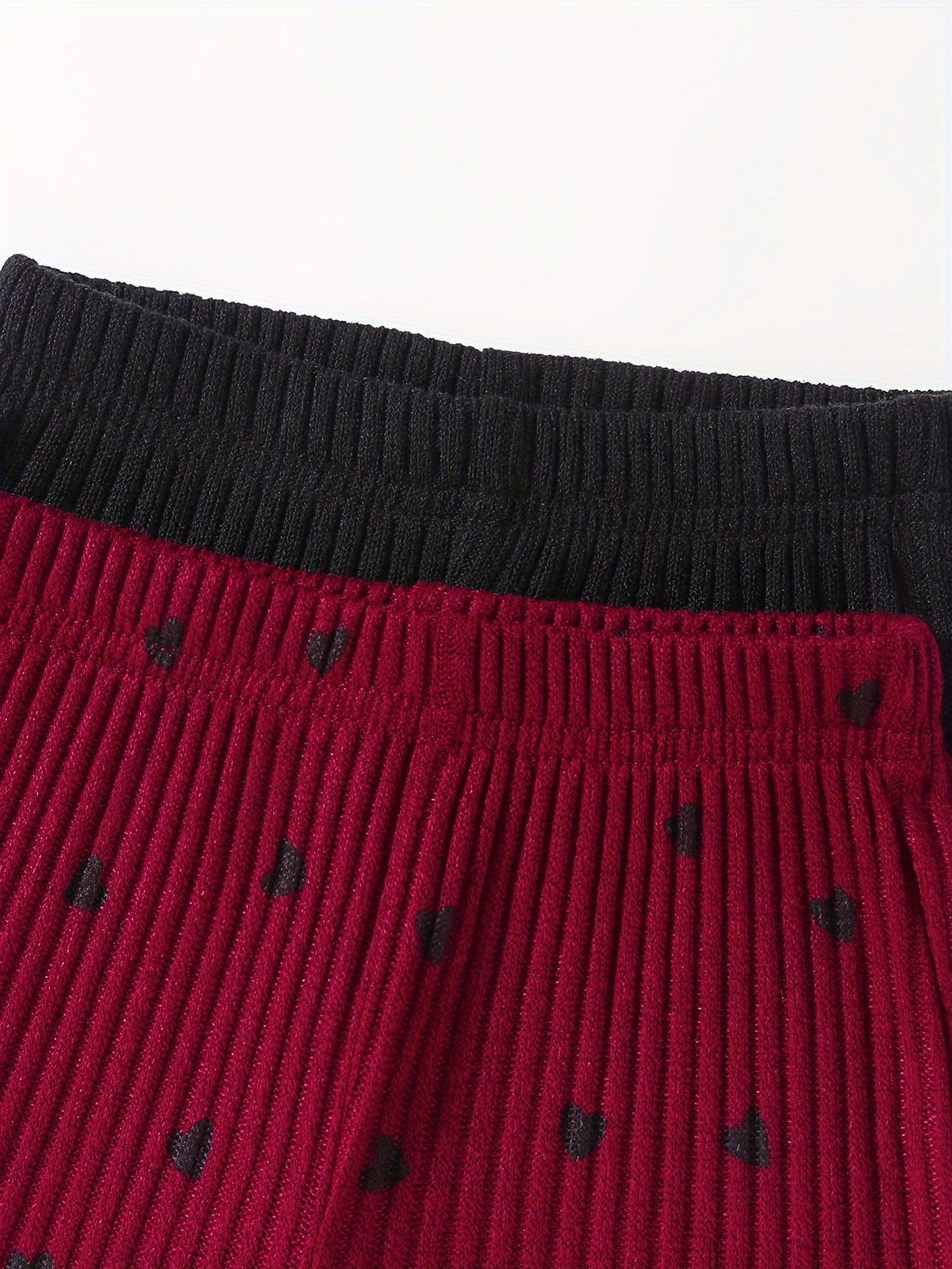 2 girls' ribbed knit outfits in black and red, with ruffled edges. Machine washable. Ideal for outdoor wear.