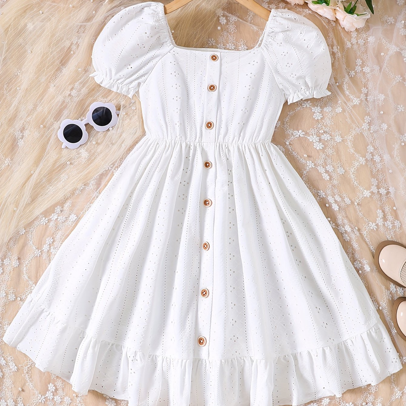 Sweet knit summer dress with charming eyelet jacquard, puff sleeves, and ruffle hem. Casual button-front white dress for young girls.