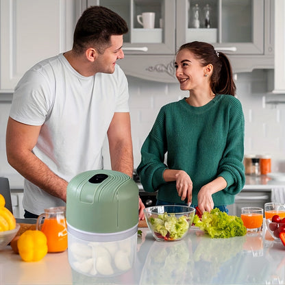 Round plastic container containing a portable multifunctional food chopper that is USB rechargeable. This versatile appliance can be used as a vegetable dicer, garlic masher, manual food processor, and electric mini kitchen appliance with a lithium