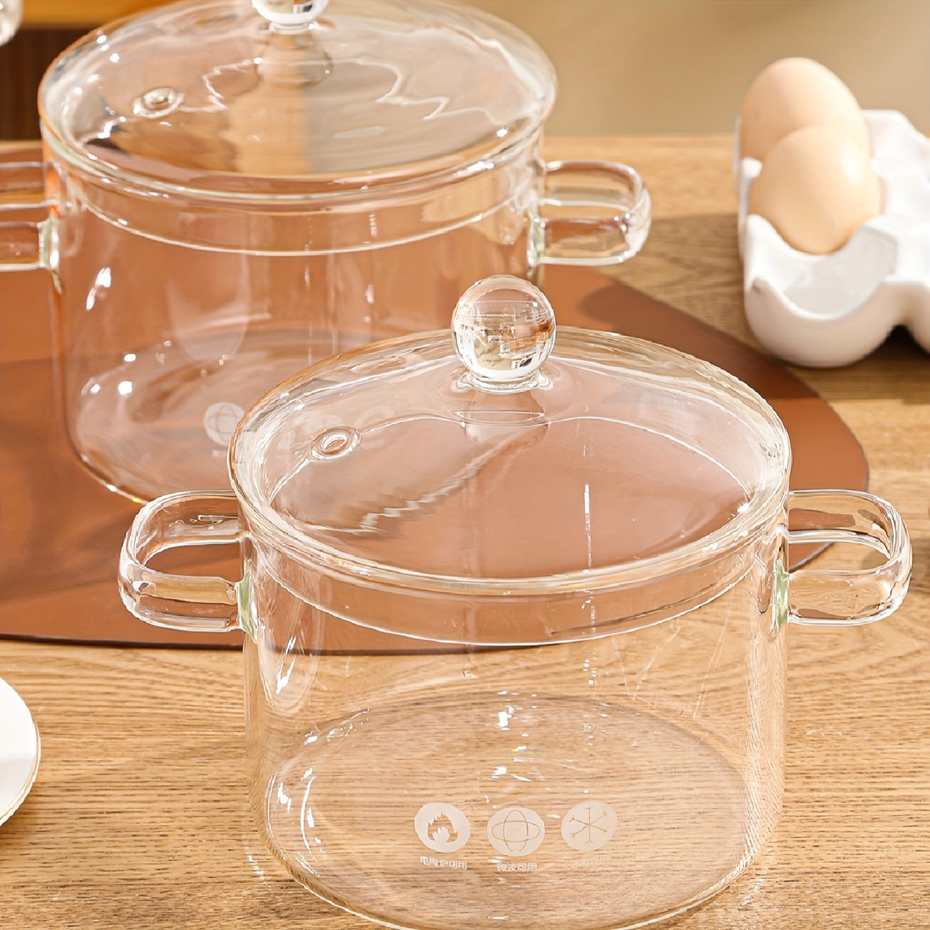 1-piece high borosilicate glass soup pot, featuring a thickened design with a lid. This small hot pot in amber color has double ears and is suitable for households. Can be used on a light fire electric pottery stove for heating and stewing.