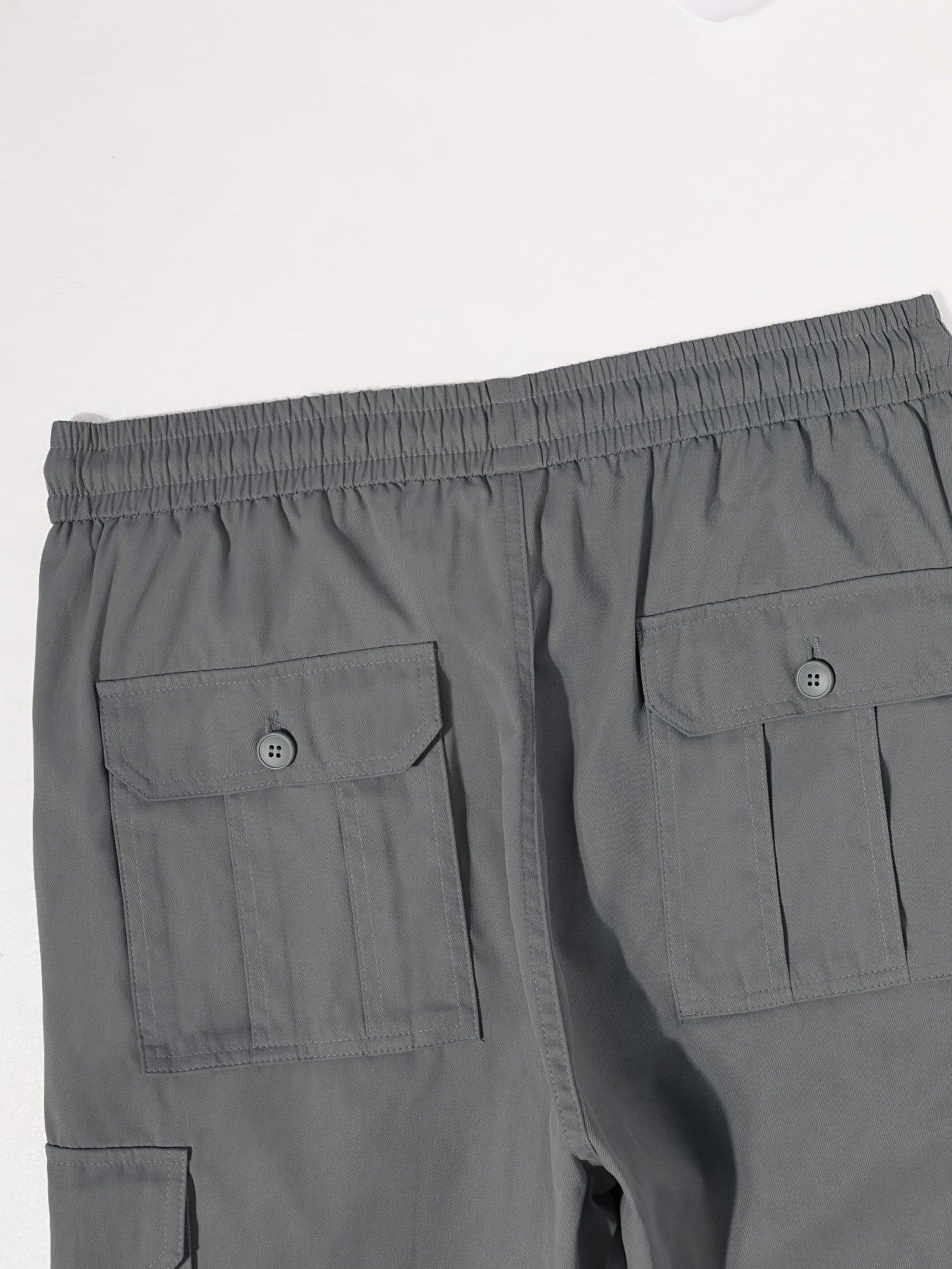 Solid color cargo pants with multiple flap pockets and a drawstring waistband, perfect for outdoor activities like hiking, fishing, and camping.