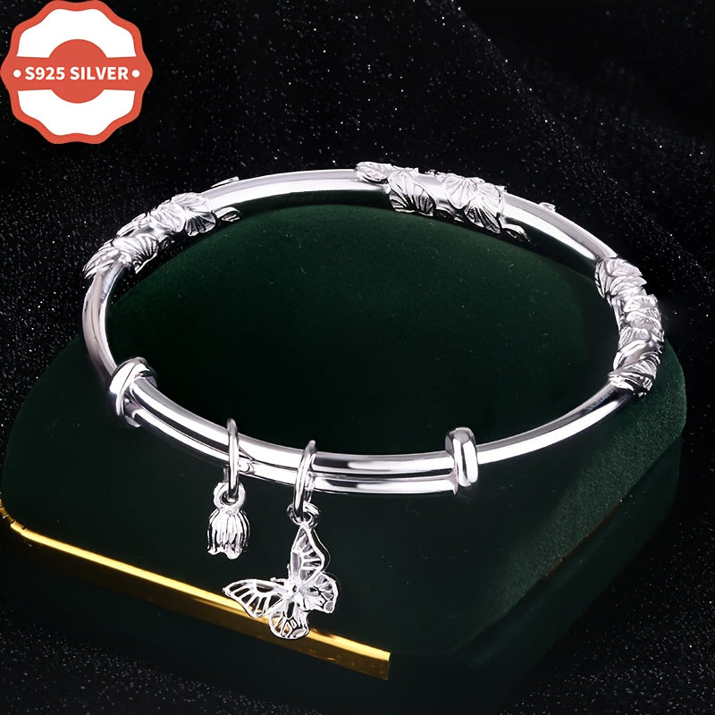 Add a touch of boho luxury to your wardrobe with this stunning 925 silver bangle bracelet featuring 18K golden plated charms. Handcrafted with floral designs, butterfly, and bell pendants, this hypoallergenic cuff is perfect for women who love unique