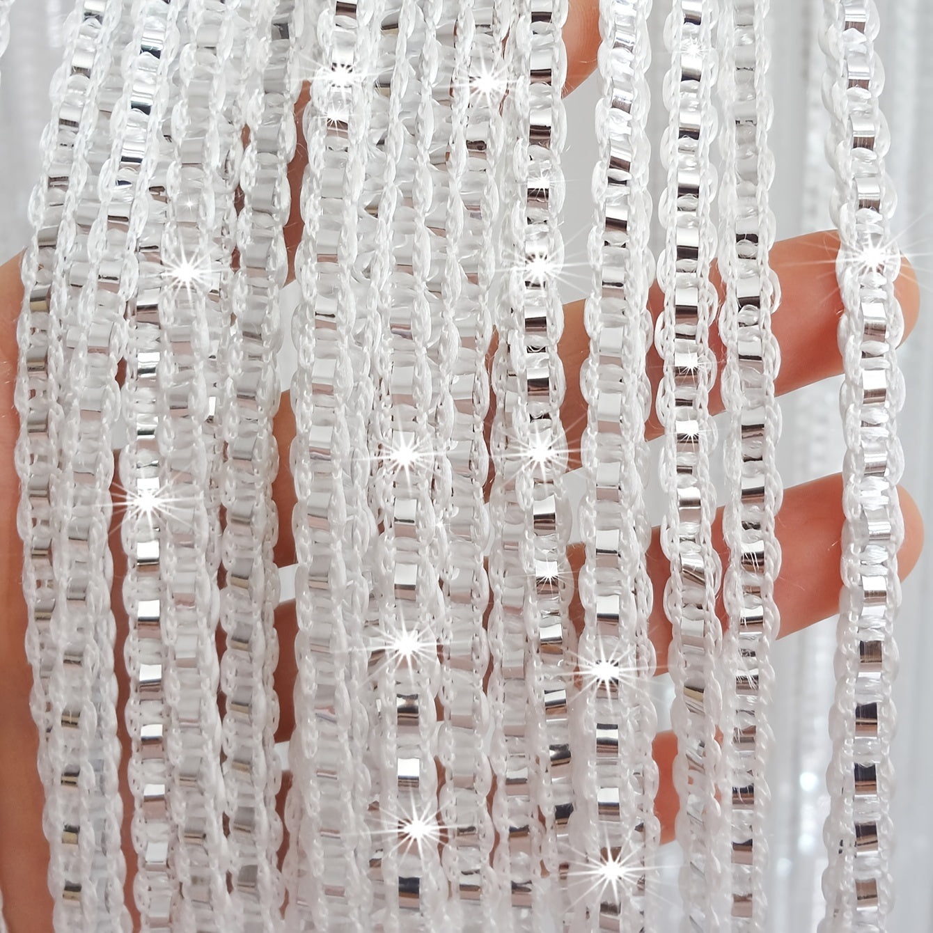 Shiny silver wire curtain with thick tassels, perfect for window or door decoration at weddings.