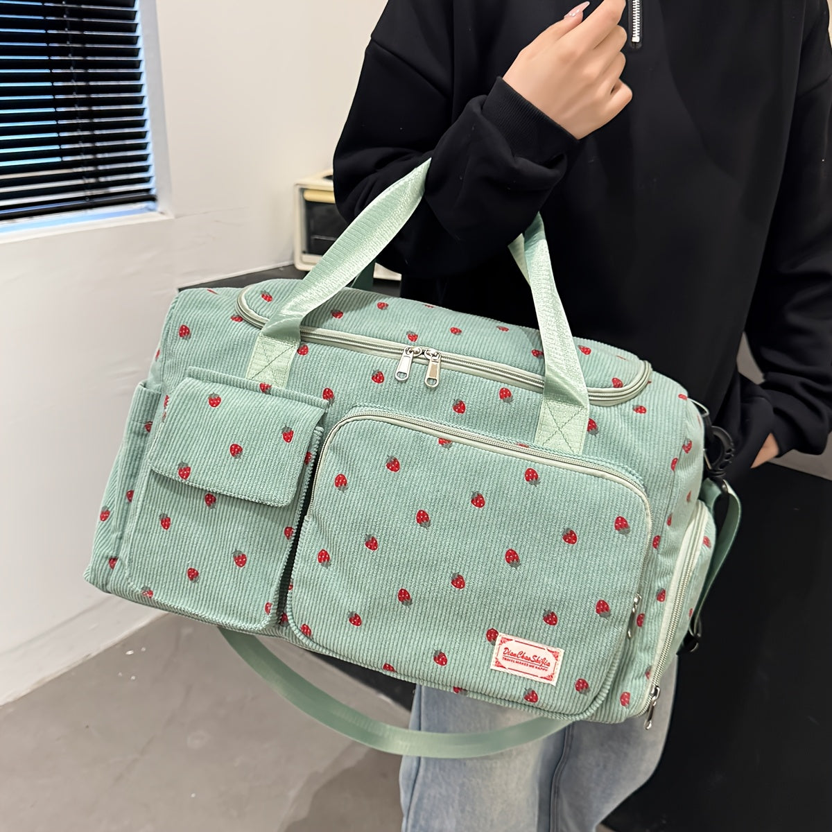 A spacious corduroy travel bag with strawberry print, wet and dry separation, shoe compartment, perfect for vacations, outings, school, crossbody use, and gym.