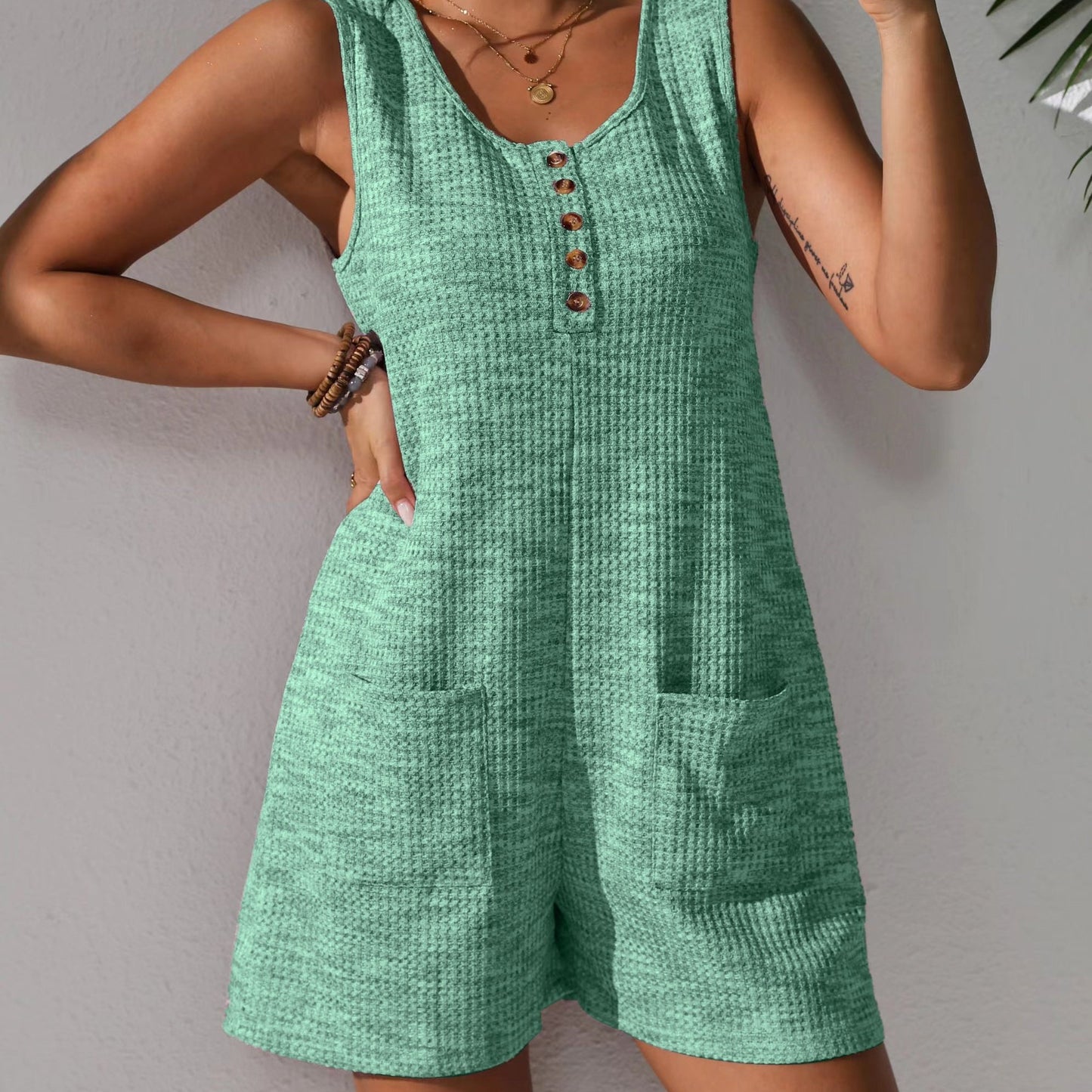 Sleeveless waffle knit romper with pockets for plus-size women in pastel pink. Comfortable and stretchy, perfect for spring/summer.