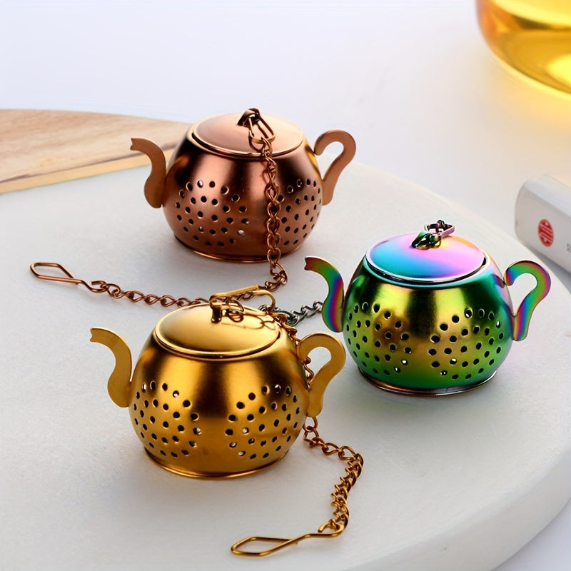 Golden rose stainless steel teapot-shaped tea strainer with uniform filter holes and hanging chain for cups.