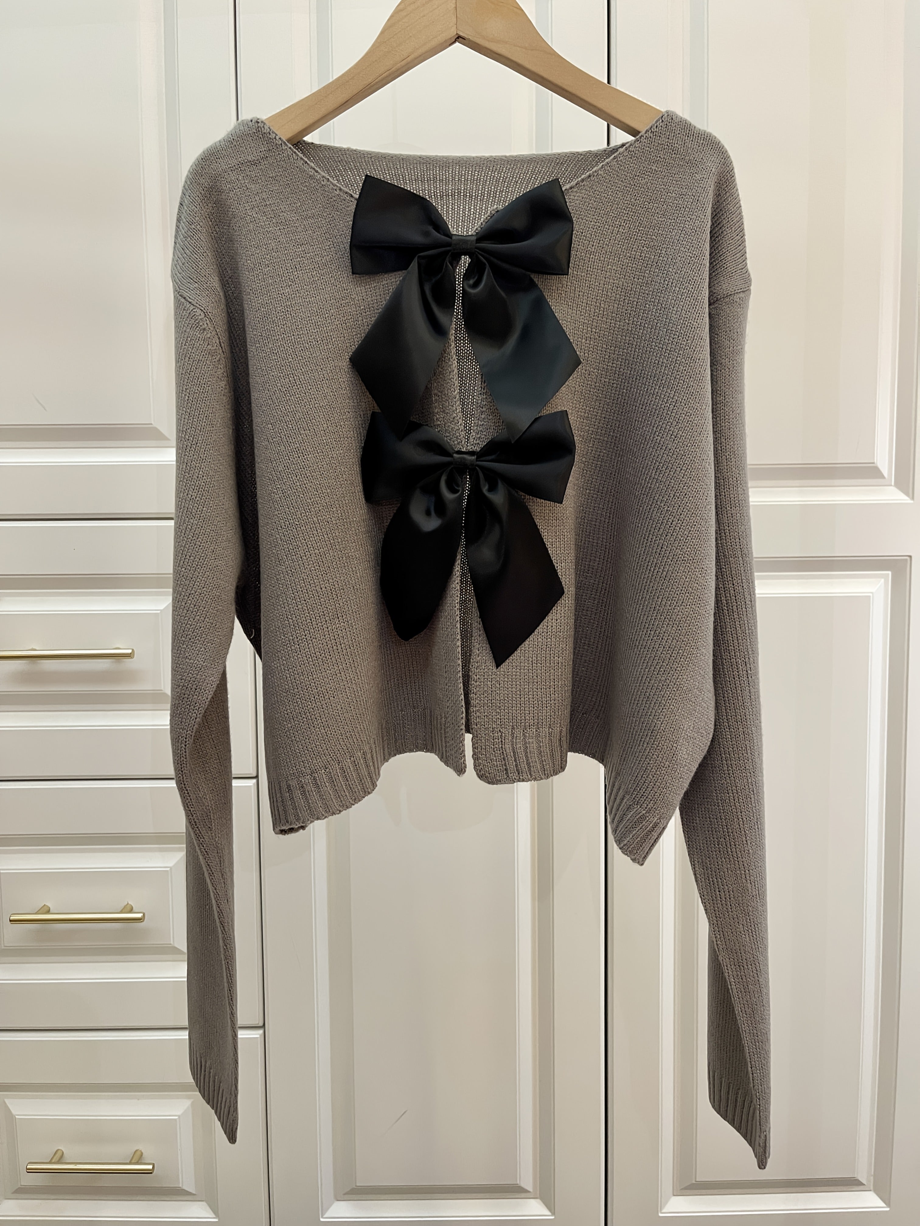 Stylish women's lightweight acrylic knit cardigan with large bow tie, perfect for spring and fall. White with black bow detail.