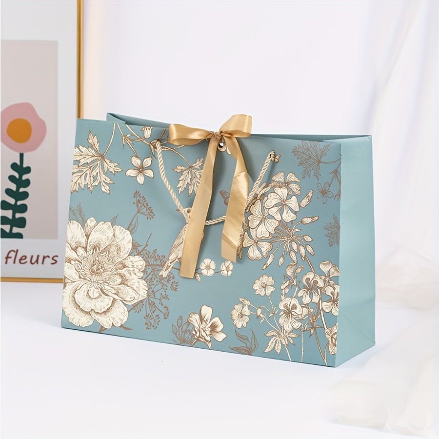 Floral paper gift bag with golden ribbon, teal background, brown, white & gray flowers, suitable for birthdays, weddings, Mother's Day, and special occasions. Features drawstring closure.