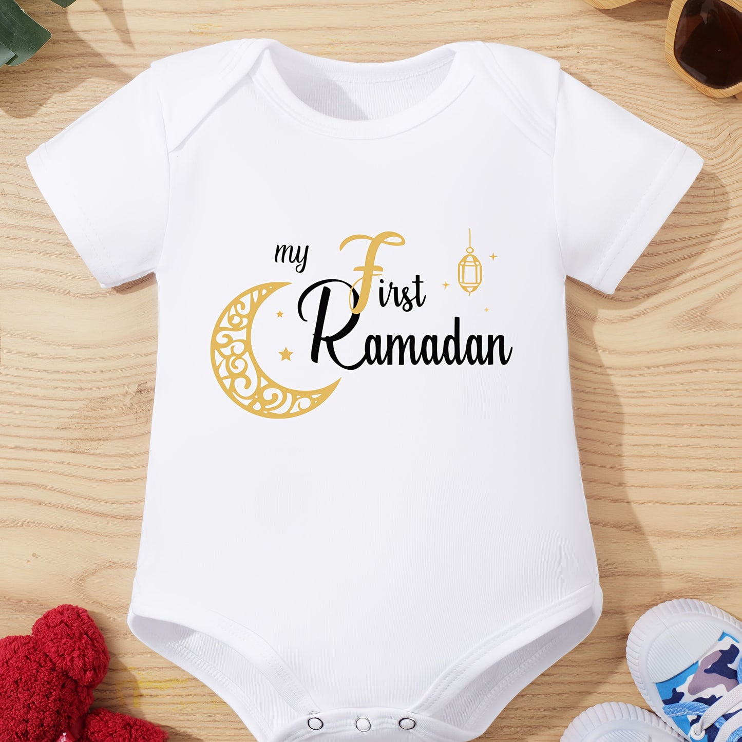 Unisex baby onesie in cotton knit with slight stretch, crew neck, button front, short sleeves, regular fit for summer. Features "My First Ramadan" letter print, suitable for outdoor wear.