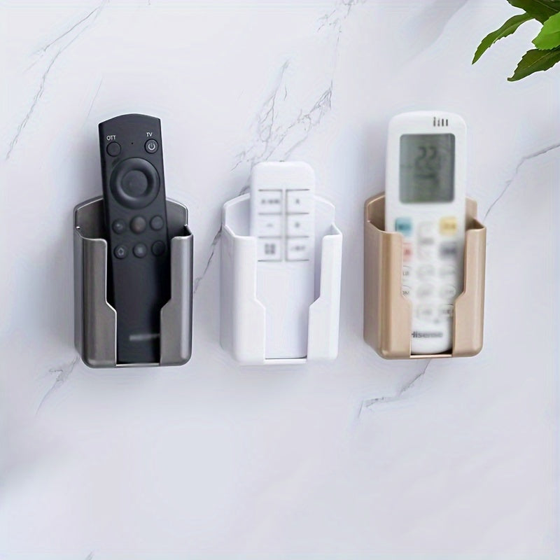 Wall mounted storage box with adhesive backing functions as a mobile phone charger holder, remote control caddy, and multipurpose holder for TV and air conditioner controllers.