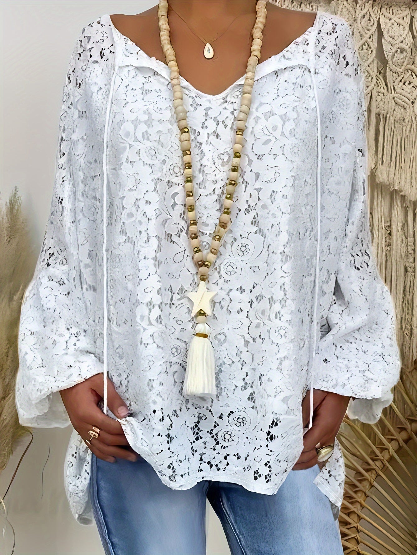 Plus size white V-neck long sleeve knit top with floral cut-out design, loose fit and lightweight polyester blend for summer wear. Features tassel necklace and lightweight knit fabric.