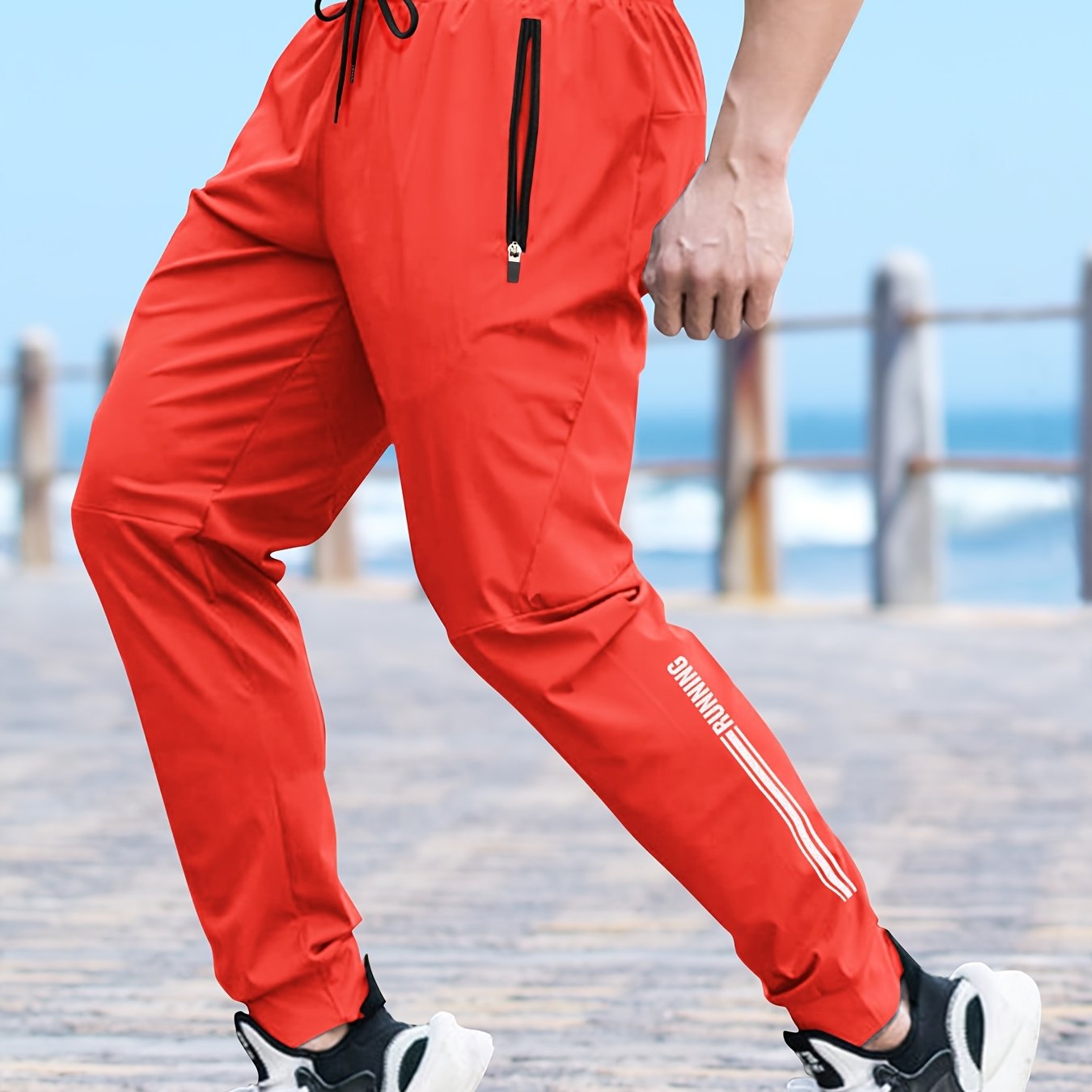 Men's solid color cuffed sports pants made of 100% polyester with moisture-wicking properties. Features a drawstring waist, loose fit, and quick-dry technology for various activities and